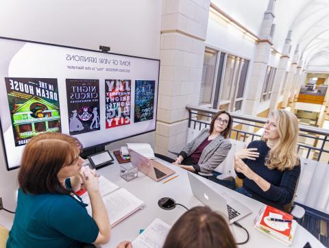 Graduate students studying reviewing a presentation around a table